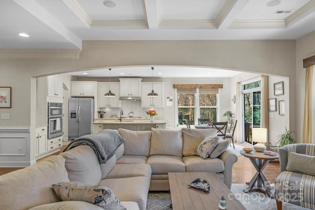 living room featuring beamed ceiling, visible vents, and wood finished floors