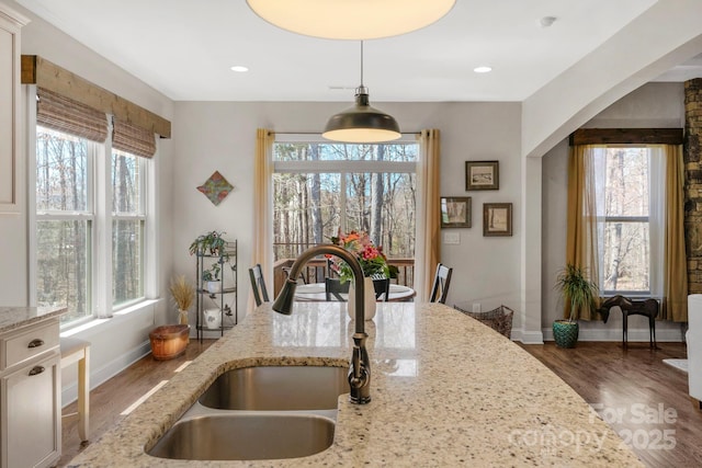 kitchen with pendant lighting, wood finished floors, baseboards, and a sink