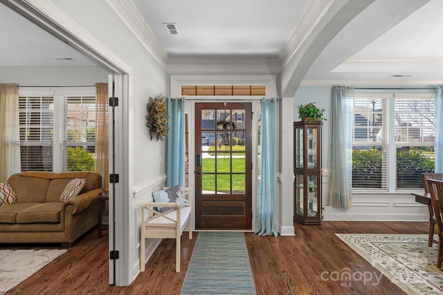 entrance foyer featuring crown molding, wood finished floors, a healthy amount of sunlight, and arched walkways