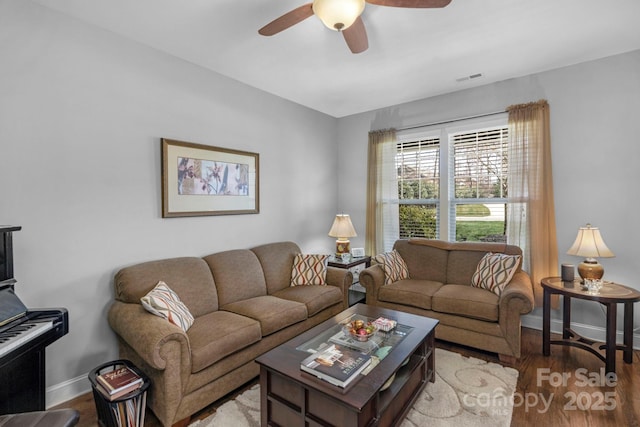 living room featuring ceiling fan, visible vents, baseboards, and wood finished floors