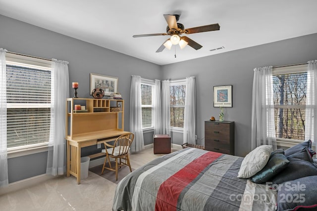 bedroom with a ceiling fan, visible vents, baseboards, and light carpet