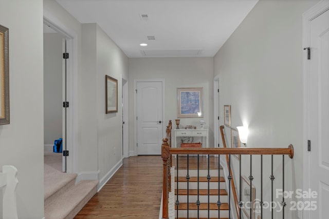 corridor with visible vents, an upstairs landing, wood finished floors, and baseboards