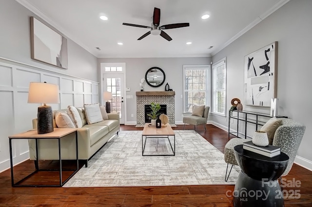 living area featuring ornamental molding, a tile fireplace, a decorative wall, and wood finished floors