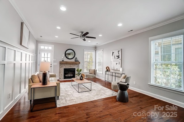 living room with plenty of natural light, ornamental molding, dark wood finished floors, and a tile fireplace