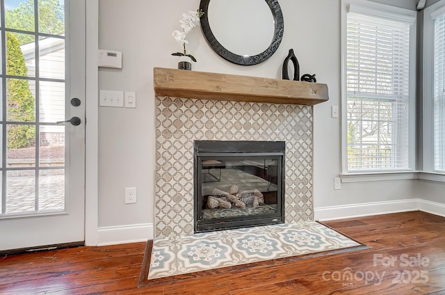 room details with wood finished floors, a tile fireplace, and baseboards