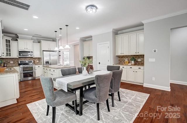 dining space with baseboards, visible vents, dark wood finished floors, and crown molding