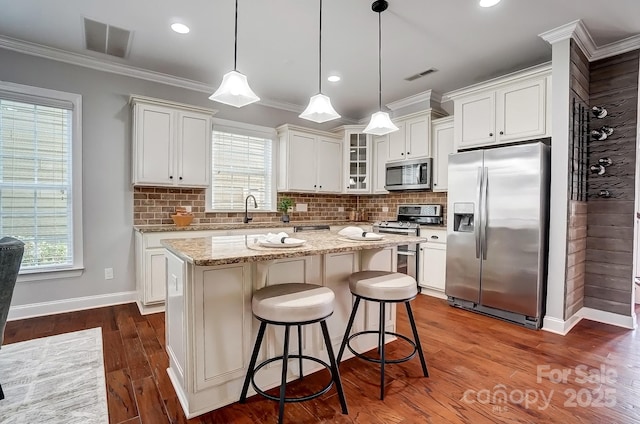 kitchen featuring a center island, stainless steel appliances, visible vents, glass insert cabinets, and white cabinets