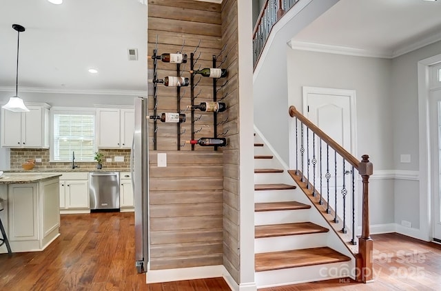 stairs featuring visible vents, baseboards, crown molding, and wood finished floors