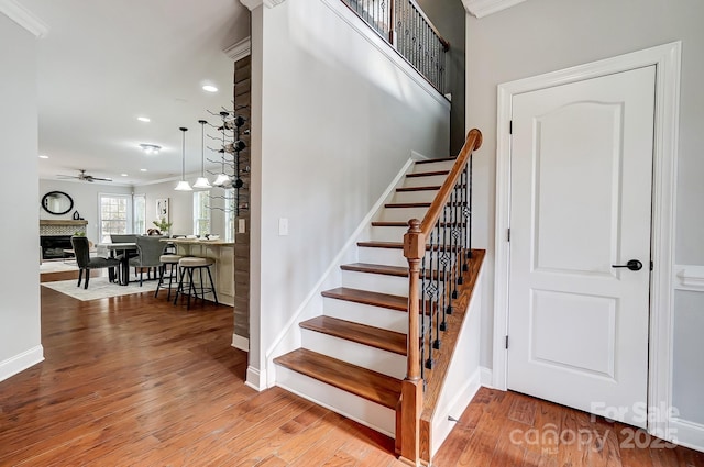 stairs featuring a fireplace, baseboards, and wood finished floors