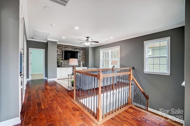 interior space featuring baseboards, wood finished floors, visible vents, and crown molding