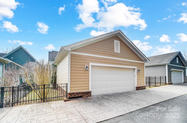 view of front facade with a detached garage, fence, and an outbuilding