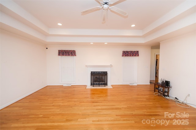 1 Carnoustie Ct, Campobello, SC 29322 - unfurnished living room featuring a tray ceiling, light hardwood / wood-style flooring, a premium fireplace, and ceiling fan