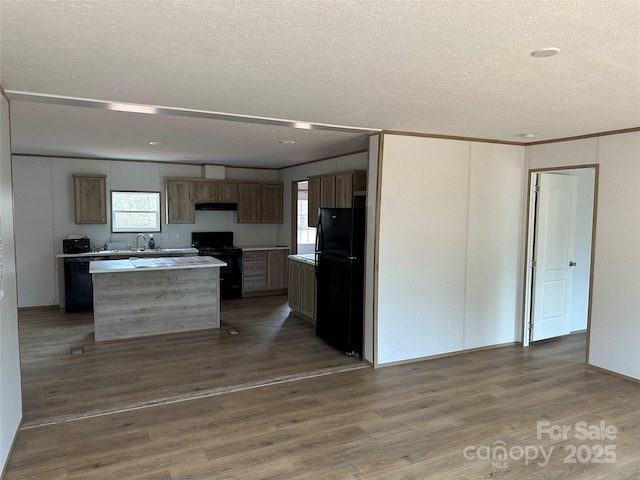 kitchen featuring sink, crown molding, black appliances, a kitchen island, and dark hardwood / wood-style flooring