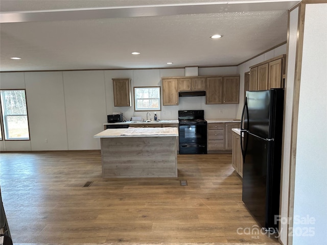 kitchen featuring sink, a center island, light wood-type flooring, and black appliances