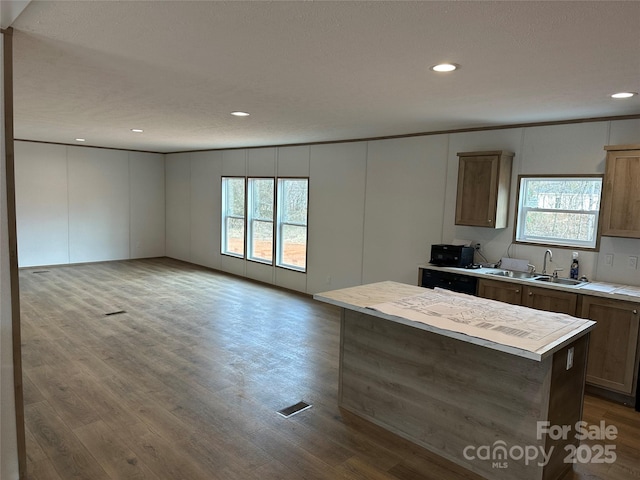 kitchen with sink, a center island, ornamental molding, dishwasher, and hardwood / wood-style flooring