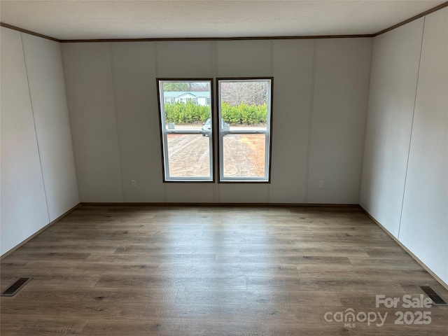 unfurnished room with hardwood / wood-style flooring and ornamental molding