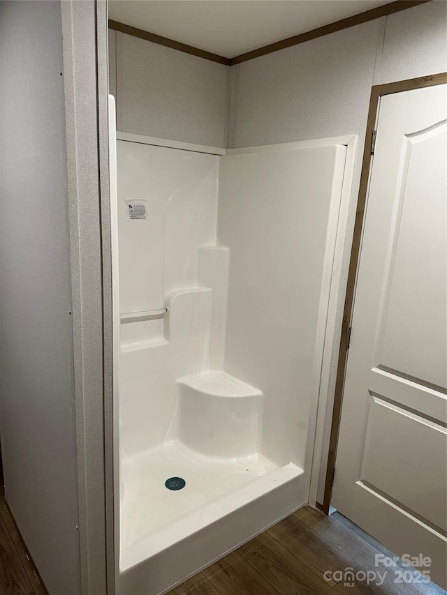 bathroom with crown molding, hardwood / wood-style flooring, and a shower