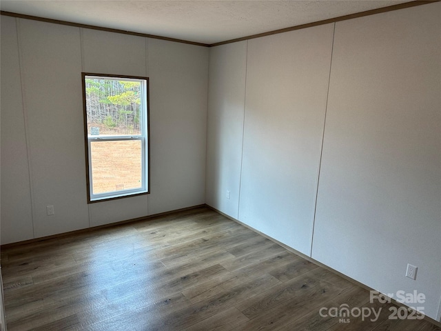 spare room with wood-type flooring and crown molding