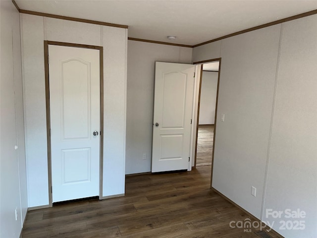 unfurnished bedroom featuring crown molding and dark hardwood / wood-style flooring