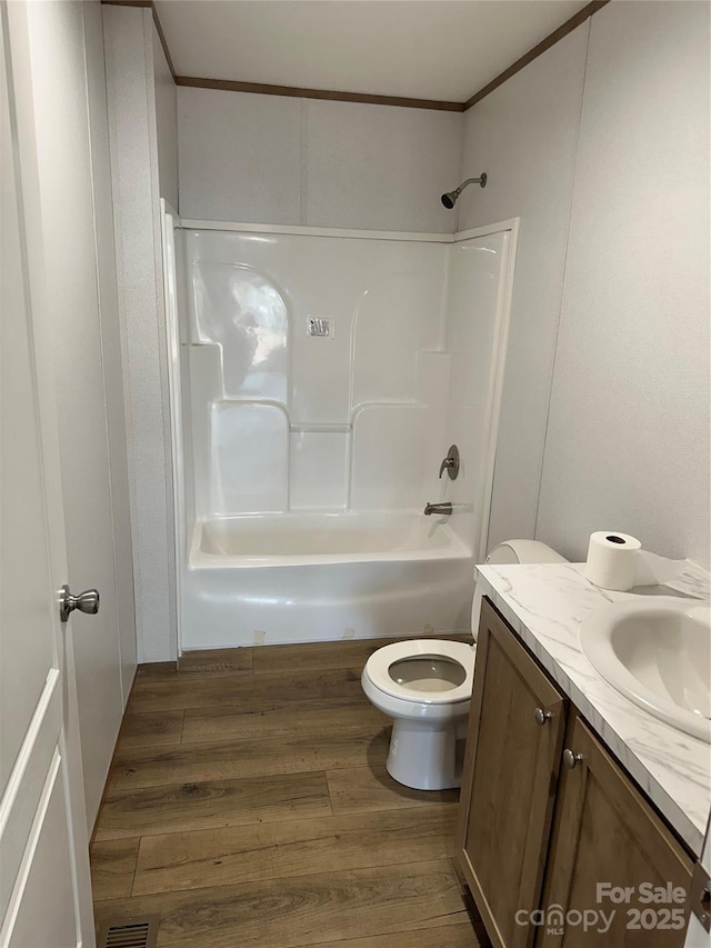 full bathroom featuring washtub / shower combination, toilet, crown molding, wood-type flooring, and vanity