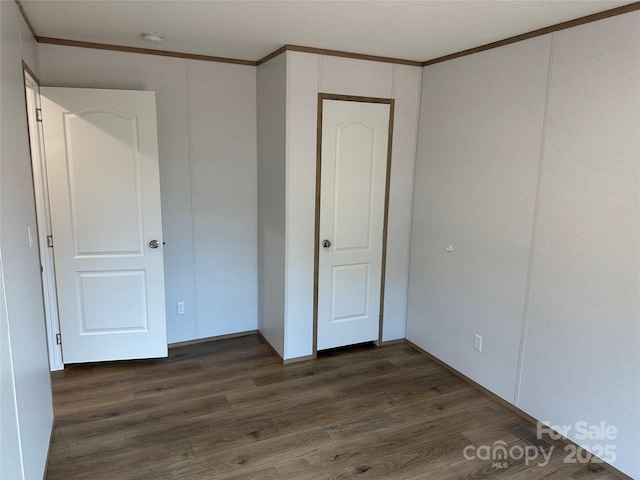 unfurnished bedroom with dark hardwood / wood-style flooring and crown molding