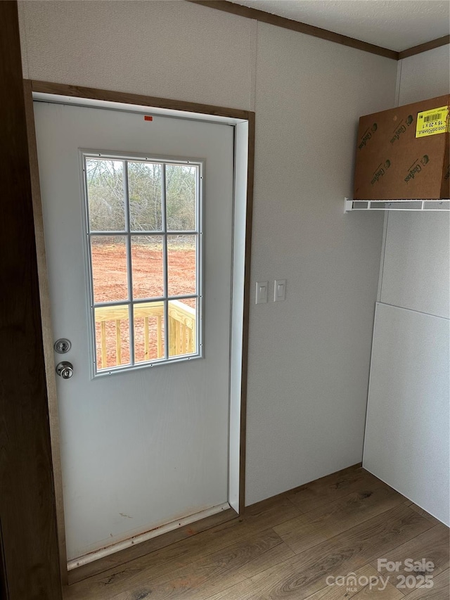 doorway with hardwood / wood-style flooring and ornamental molding