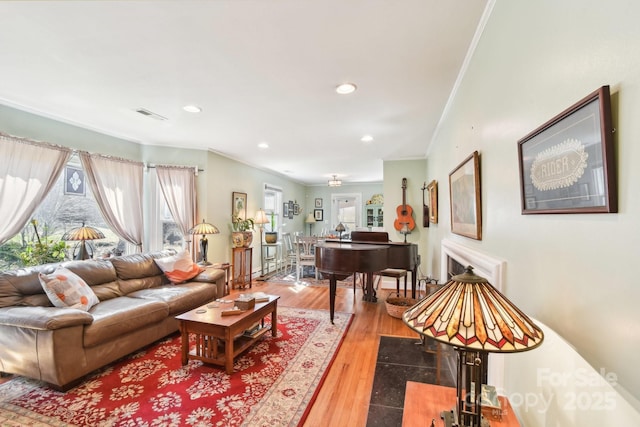 living area featuring recessed lighting, wood finished floors, visible vents, and crown molding