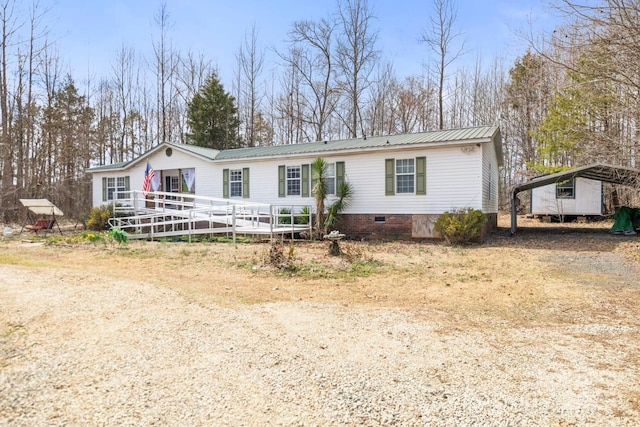 manufactured / mobile home featuring dirt driveway, metal roof, crawl space, a deck, and a carport