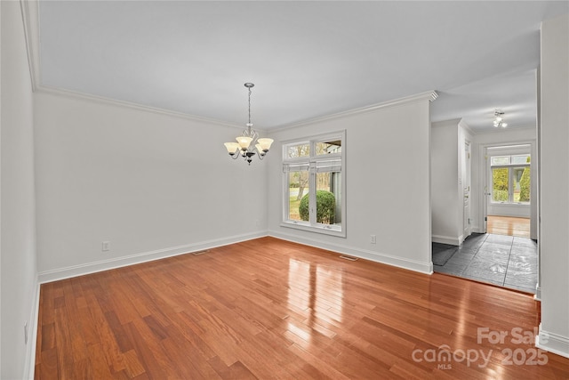 unfurnished dining area featuring hardwood / wood-style flooring, crown molding, and an inviting chandelier