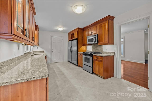 kitchen featuring sink, stainless steel appliances, light stone countertops, light tile patterned flooring, and decorative backsplash