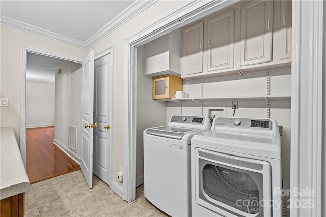 laundry room with cabinets, washing machine and clothes dryer, ornamental molding, and light tile patterned flooring