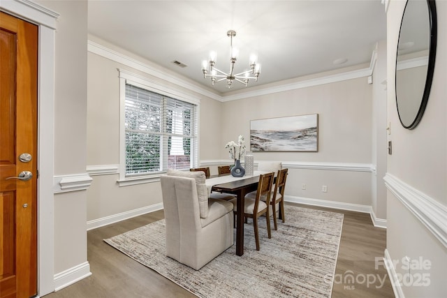 dining area with crown molding, dark wood-type flooring, and a chandelier