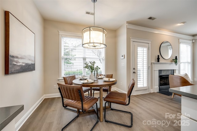 dining area featuring a healthy amount of sunlight, a high end fireplace, and light hardwood / wood-style floors