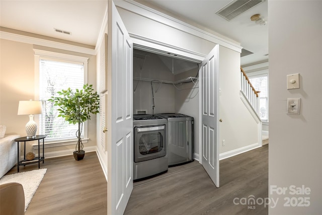 washroom with wood-type flooring, washer and clothes dryer, and a healthy amount of sunlight