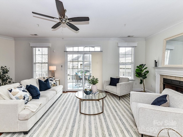 living room featuring a fireplace, ornamental molding, ceiling fan, and light hardwood / wood-style floors