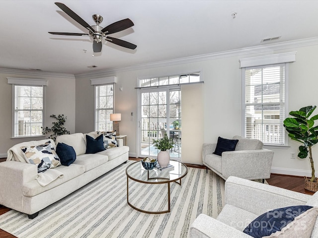 living room featuring a healthy amount of sunlight, wood-type flooring, ornamental molding, and ceiling fan