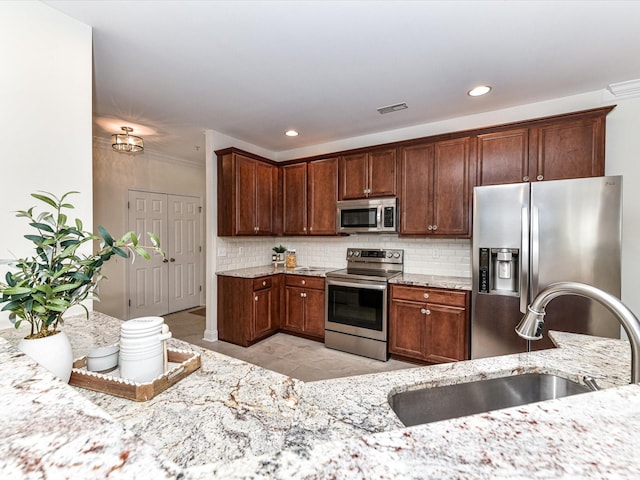 kitchen with stainless steel appliances, backsplash, light stone counters, and sink