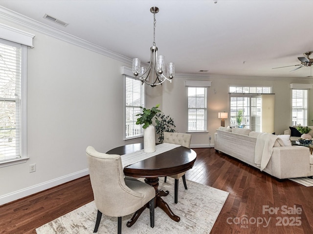 dining area featuring ornamental molding, dark hardwood / wood-style floors, a wealth of natural light, and ceiling fan with notable chandelier