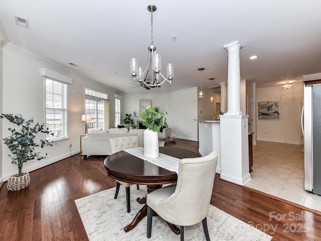 dining space featuring light hardwood / wood-style floors, ornate columns, and ornamental molding