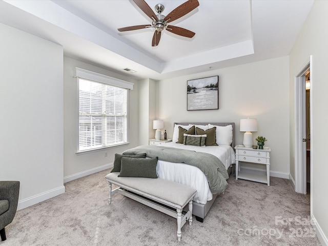 carpeted bedroom featuring ceiling fan and a raised ceiling