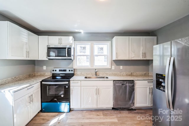 kitchen featuring appliances with stainless steel finishes, sink, white cabinets, and light hardwood / wood-style floors