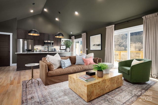 living area featuring high vaulted ceiling, recessed lighting, and light wood-style flooring