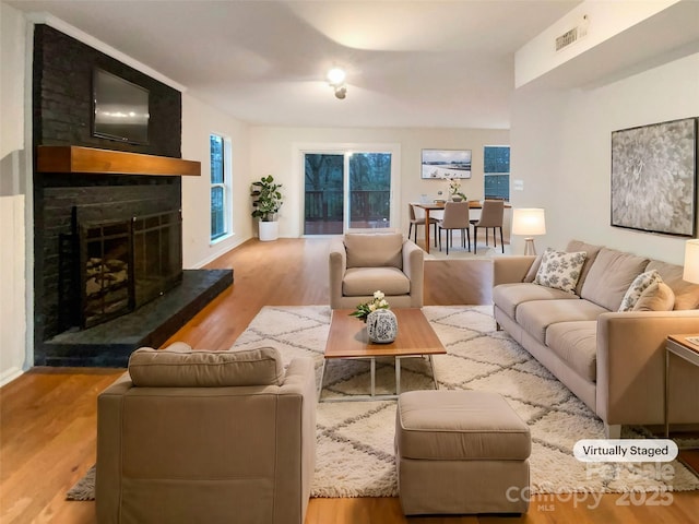 living area with a large fireplace, visible vents, and wood finished floors