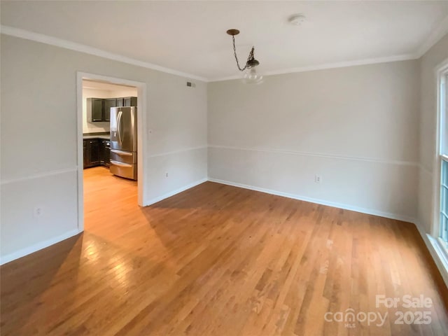 empty room featuring ornamental molding, wood finished floors, visible vents, and baseboards