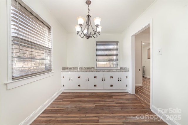 interior space with ornamental molding, dark wood-style flooring, baseboards, and a notable chandelier