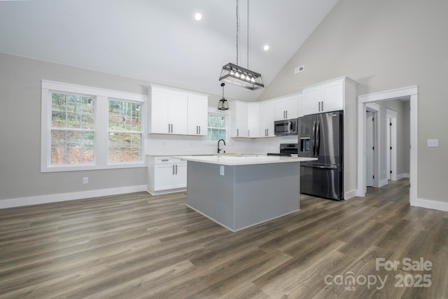 kitchen with stainless steel appliances, white cabinetry, a kitchen island with sink, and decorative light fixtures