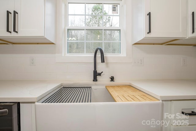 kitchen featuring white cabinetry, sink, backsplash, and light stone countertops