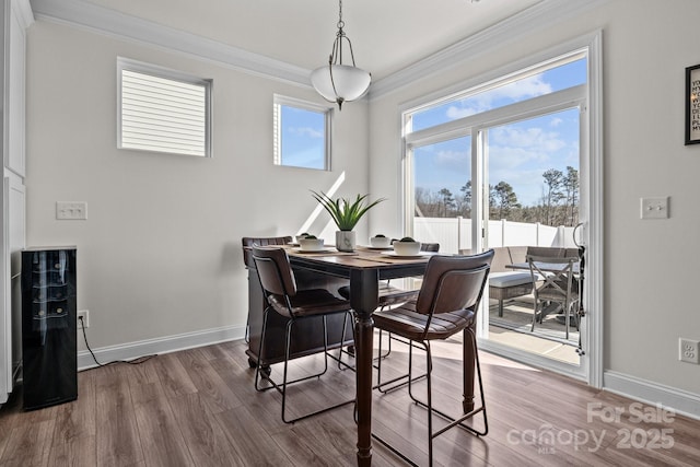 dining space featuring wood finished floors, baseboards, and ornamental molding