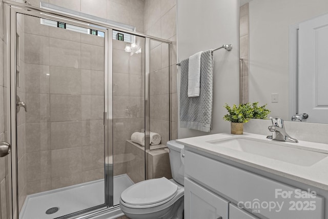 full bath with a shower stall, vanity, and toilet