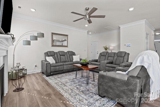living area featuring baseboards, ornamental molding, visible vents, ceiling fan, and wood finished floors